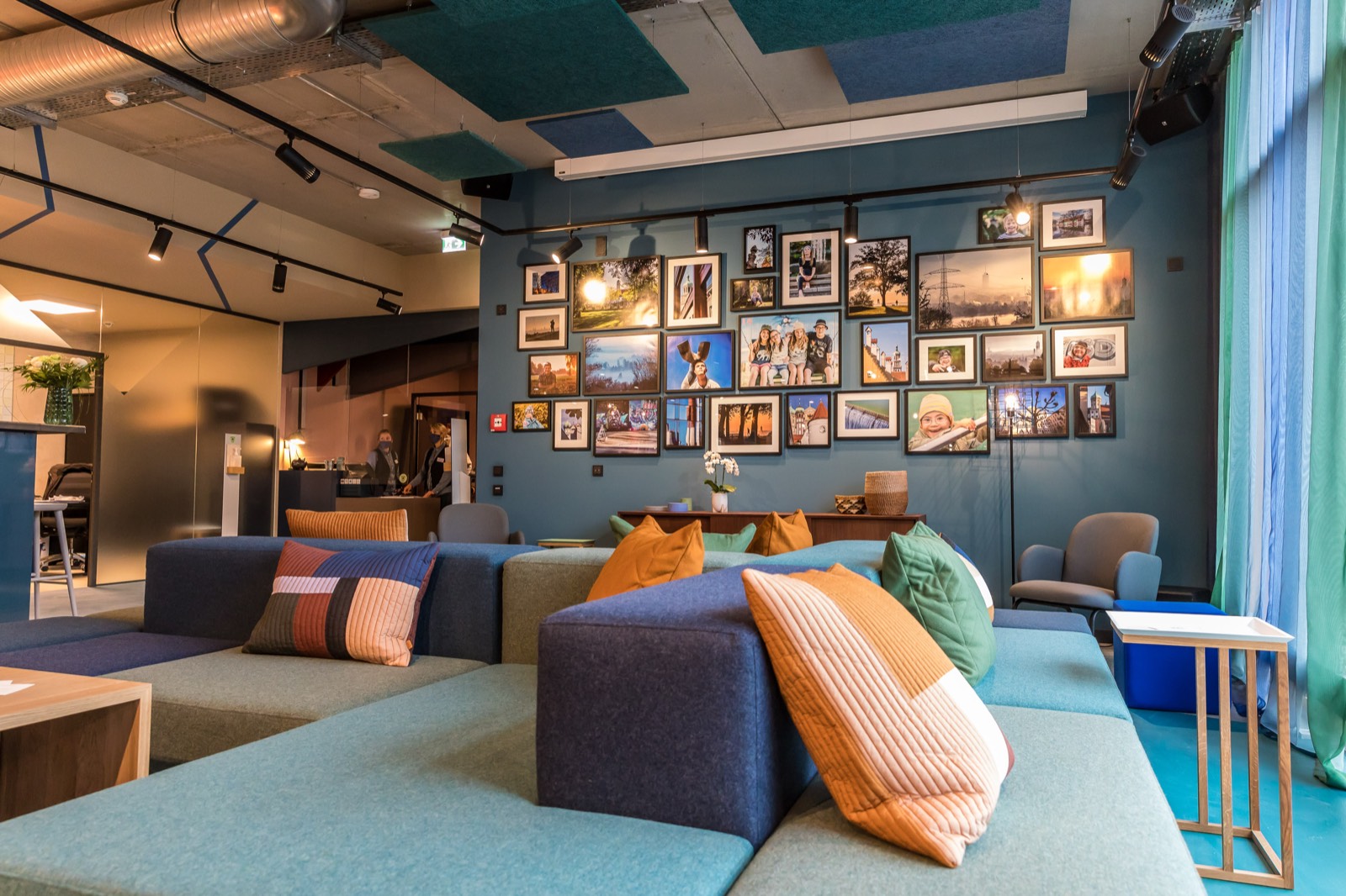 einsmehr Hotel Augsburg – Lobby mit Sofalandschaft und Bilderwand